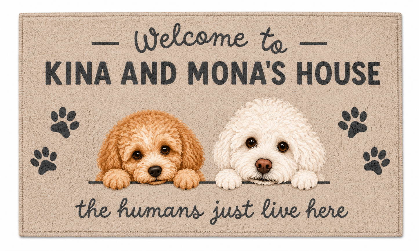 A rectangular doormat with a beige background featuring the text 'Welcome to KINA AND MONA'S HOUSE' and 'the humans just live here,' plus two illustrated puppy portraits and black paw prints.
